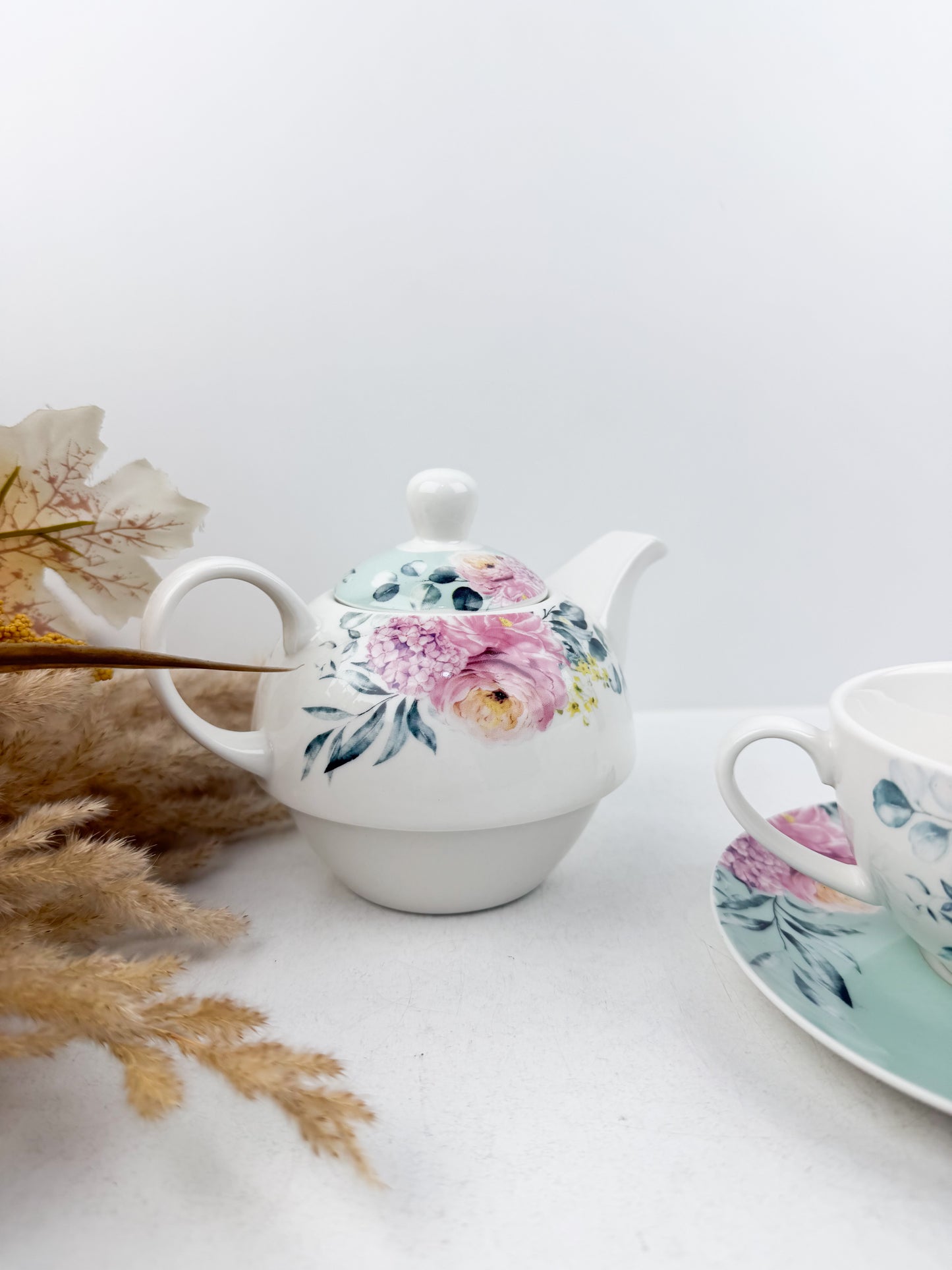 Théière élégante d'une tasse accompagnée de sous-tasse raffinée de motif floral