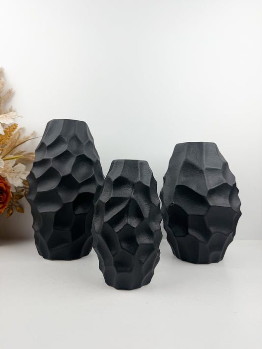 Trio de vases en noir carbone aux formes sculpturales épurées.