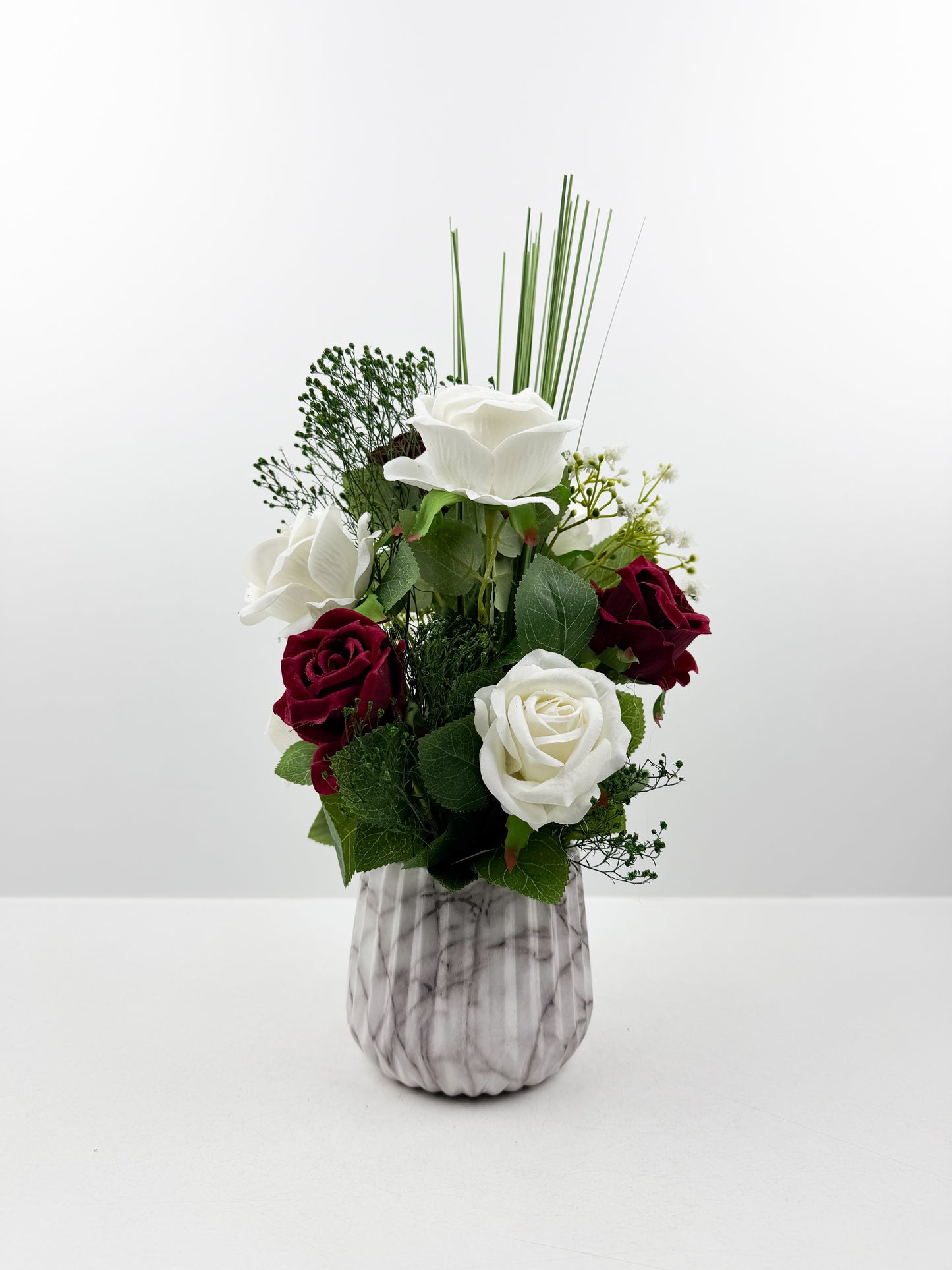 Fleurs artificielles blanches et rouges d'une élégance intemporelle dans un vase en forme de marbre raffiné.