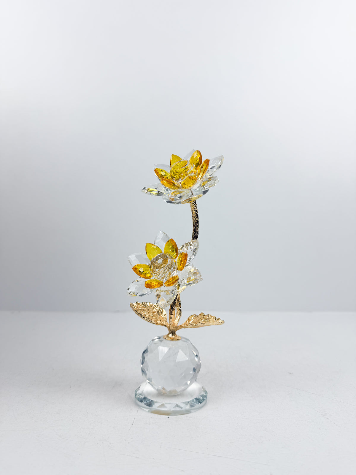 Fleur décorative dorée en cristal sur socle sphérique élégant.