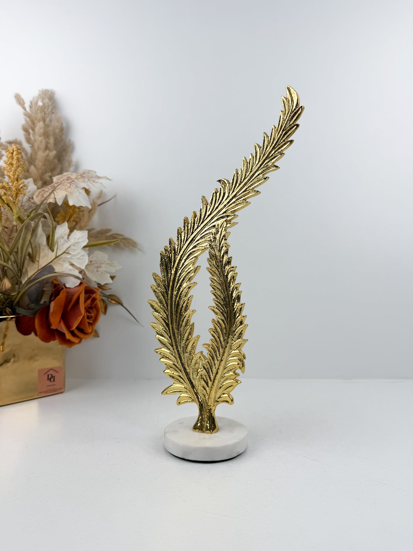 Sculpture décorative élégante représentant une feuille de fougère stylisée en métal doré.