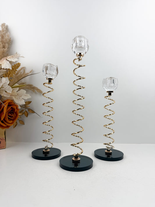 Trio de Bougeoirs en cristal doré sur un socle noir.