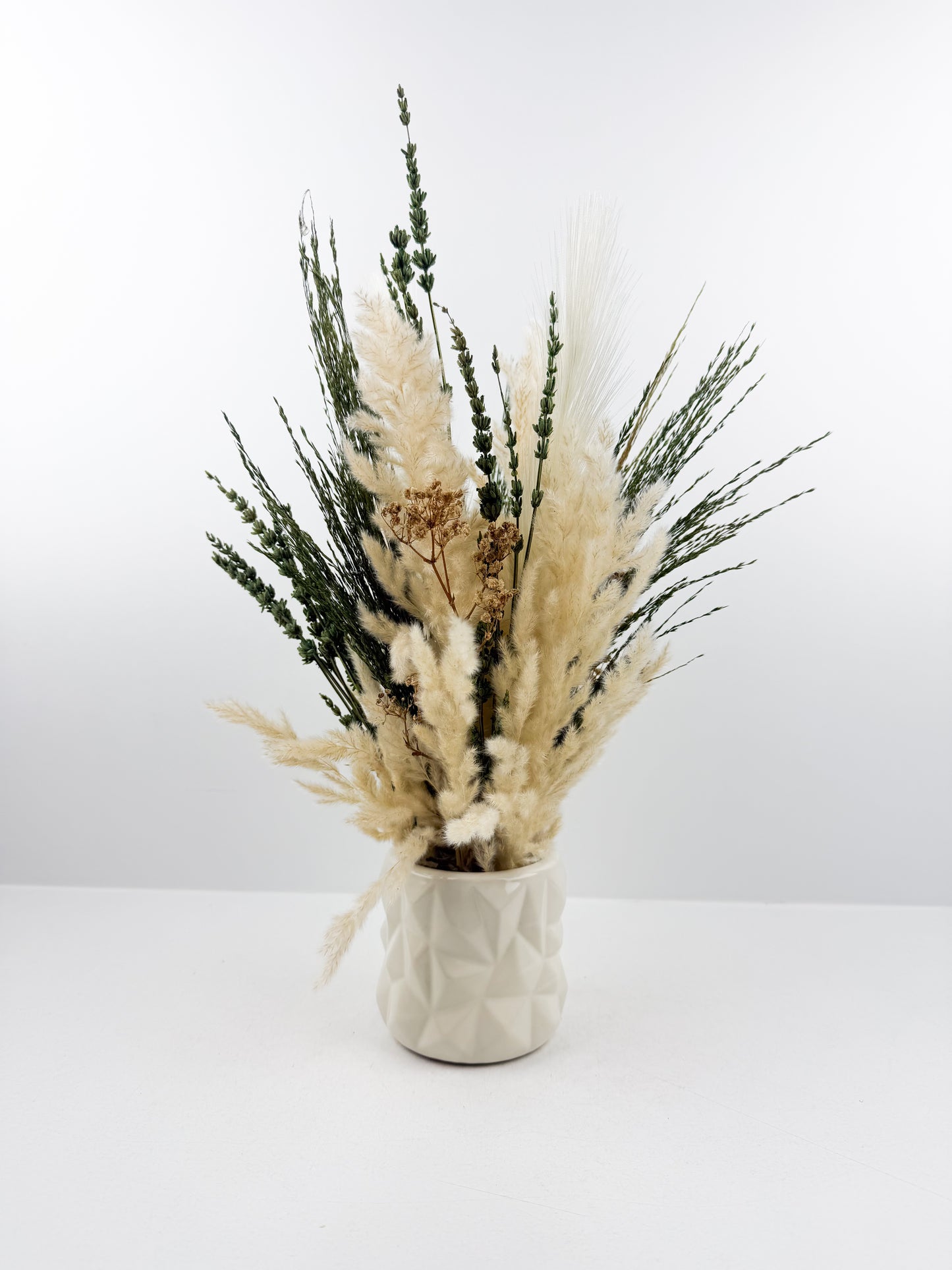 Fleurs séchées aux teintes naturelles de beige et vert, accompagnée d'un vase en céramique haut de gamme