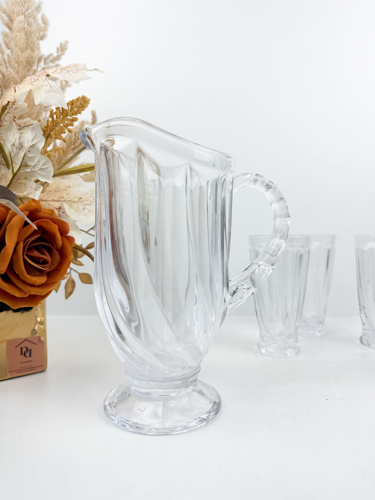 Service en verre transparent composé d'une carafe et de six verres assortis à motifs géométriques.