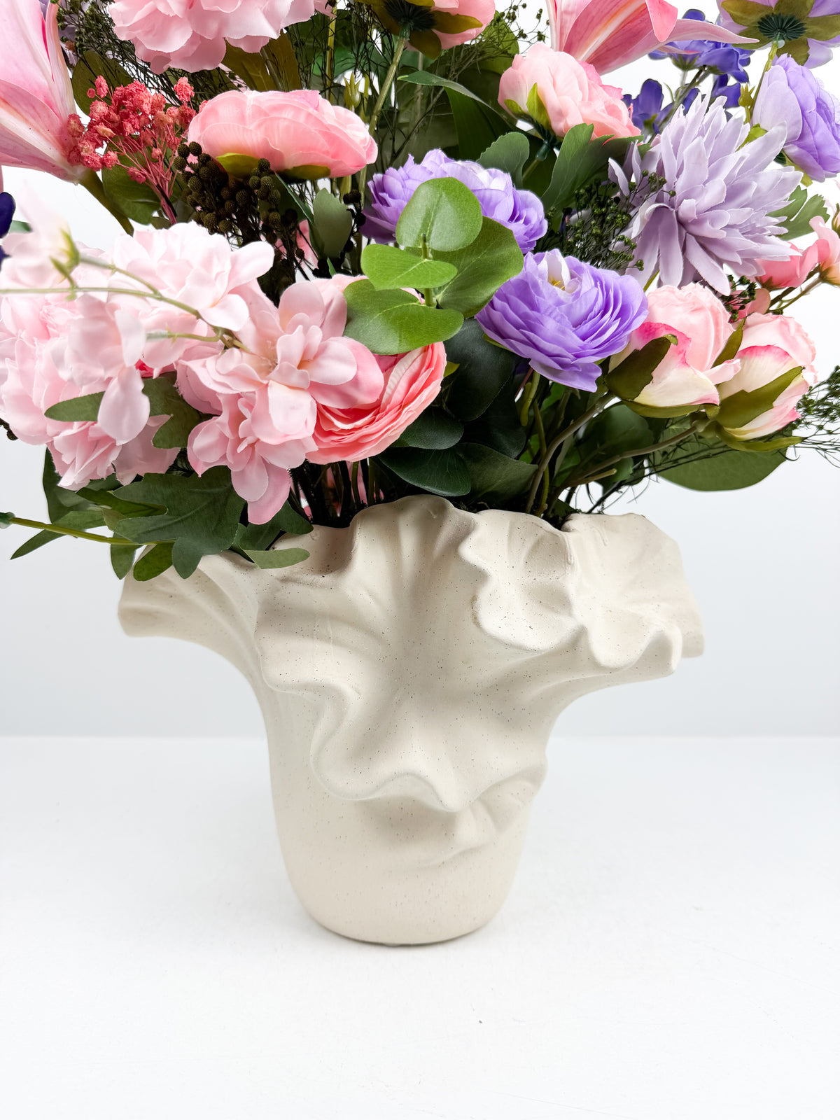 Fleurs artificielles présenté dans un original vase design sculpté en céramique à relief.