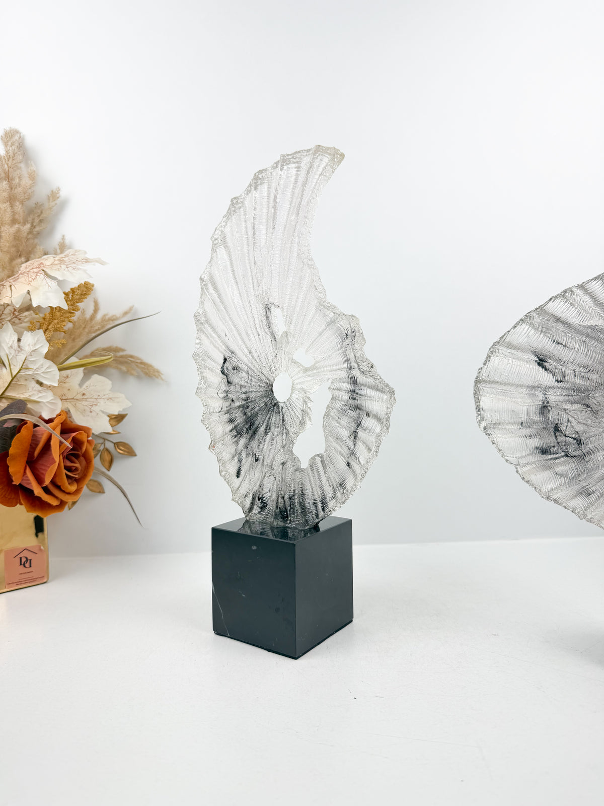 Sculpture décorative plissée en résine sur un socle en cristal noir élégant.