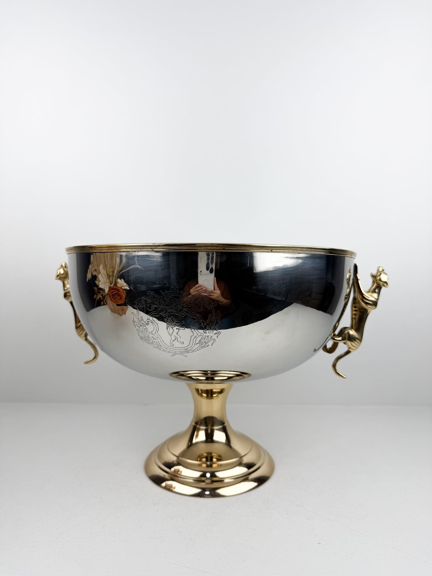 Présentoir très chic et luxe en métal miroir avec pieds dorés et poignées en forme de tigre.