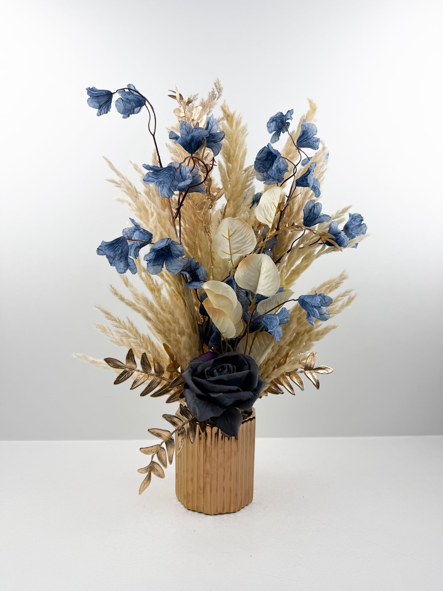 Fleurs séchées dans un vase en céramique doré au design élégant et luxueux.