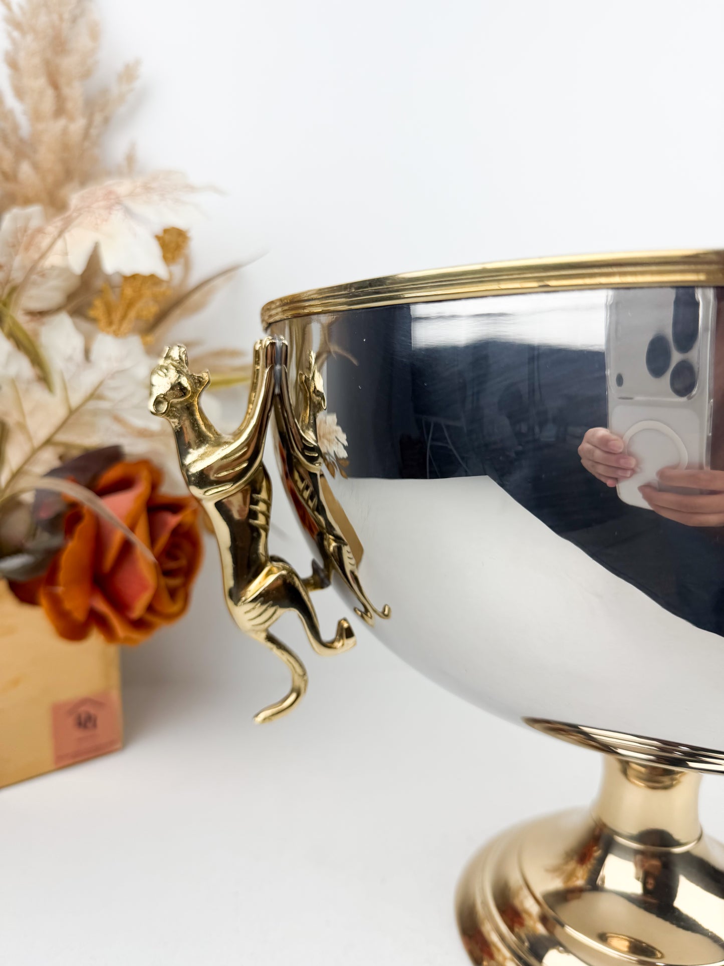 Présentoir très chic et luxe en métal miroir avec pieds dorés et poignées en forme de tigre.