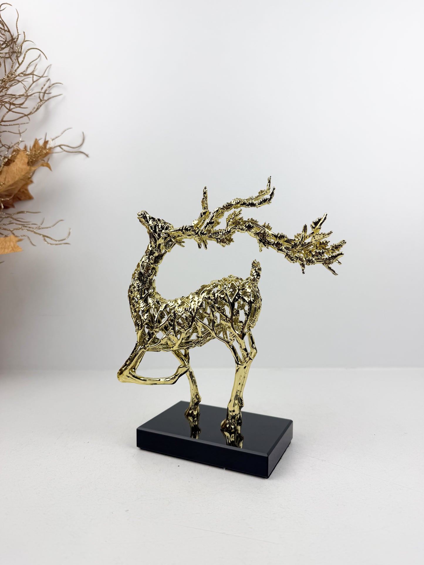 Sculpture de gazelle dansante en métal doré sur un socle noir en cristal , incarnant l'élégance et la grâce.