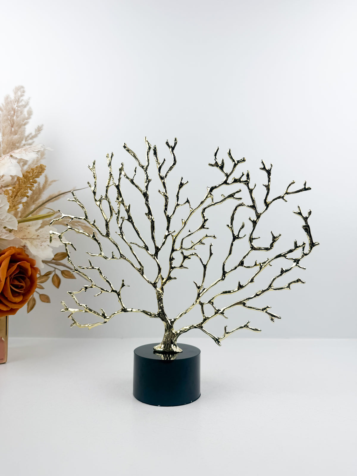 Arbre décoratif sculptural doré sur un socle en cristal noir.