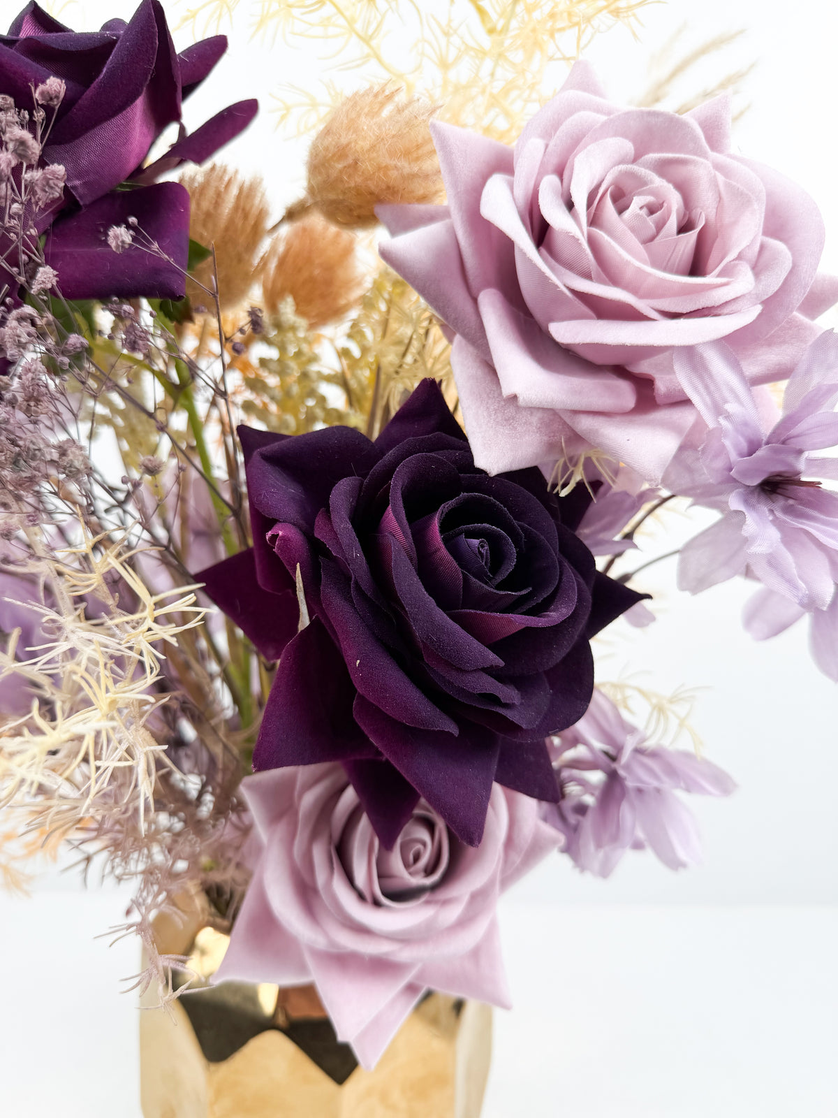 Fleurs séchées délicates dans un élégant vase géométrique en céramique dorée.