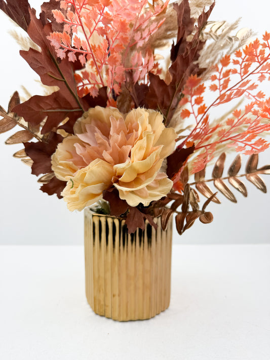 Fleurs séchées rehaussée d'une fleur rose délicate dans un vase en céramique doré aux lignes épurées
