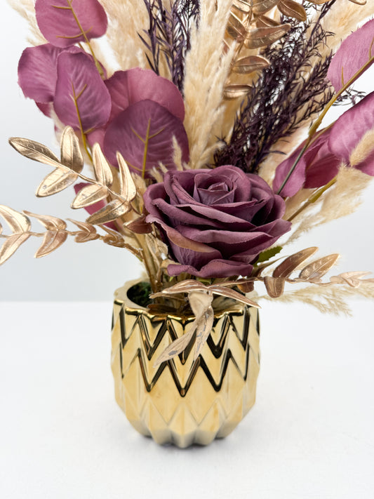 Fleurs séchées rehaussée d'une fleur violet délicate dans un vase en céramique doré aux lignes épurées