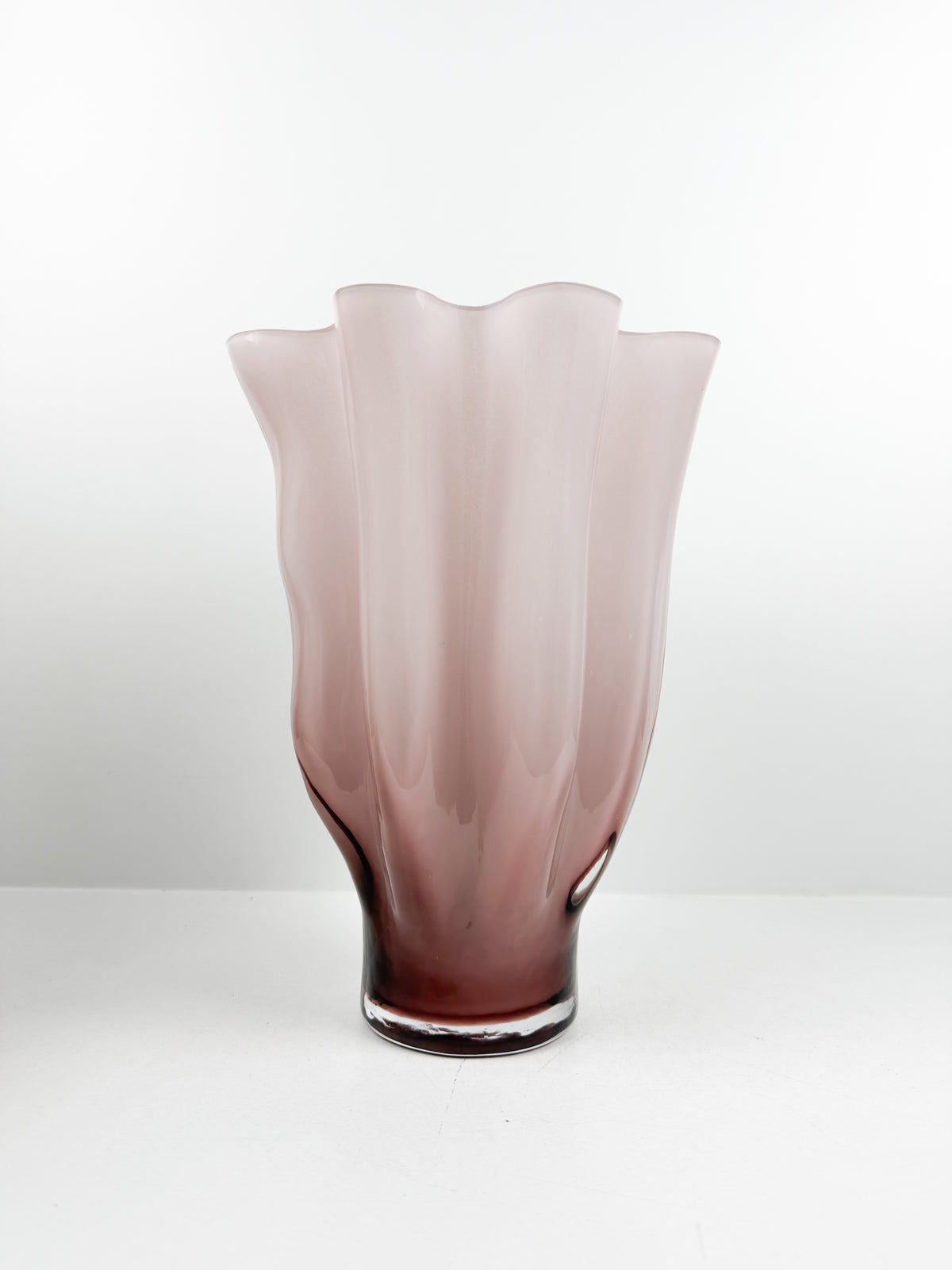 Vase décoratif sculpté rose aux bords ondulés et motifs plissés.