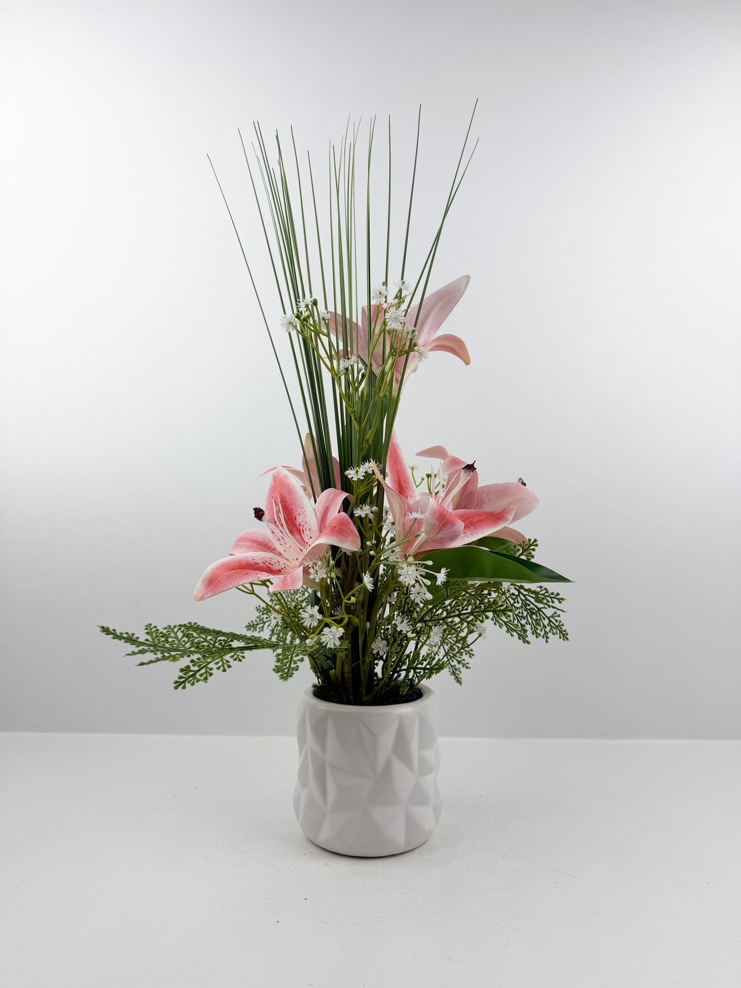 Fleurs artificielles roses  délicates dans un élégant pot blanc en céramique de luxe.
