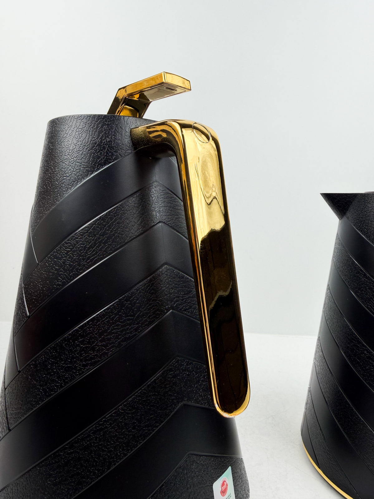 Duo de thermos isothermes noirs mats avec motifs chevrons en relief, anses et détails dorés.