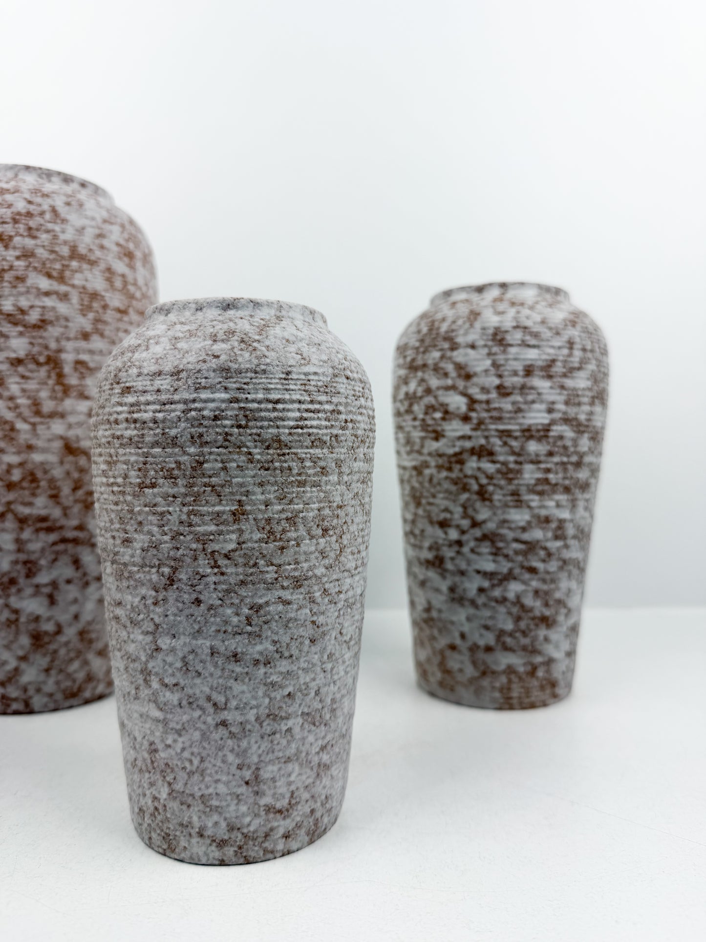 Trio de vases aux teintes marron et blanc en céramique alliant élégance et raffinement.