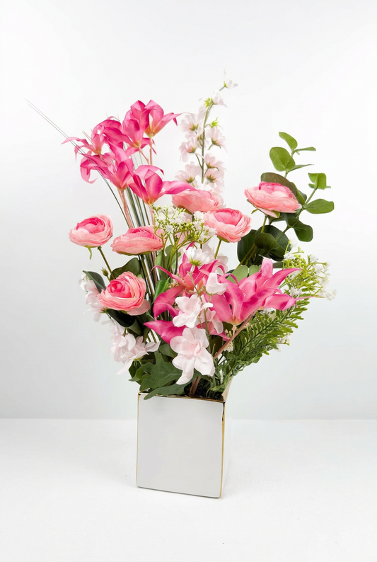 Fleurs artificielles roses et blanches dans un vase carré en céramique blanc.