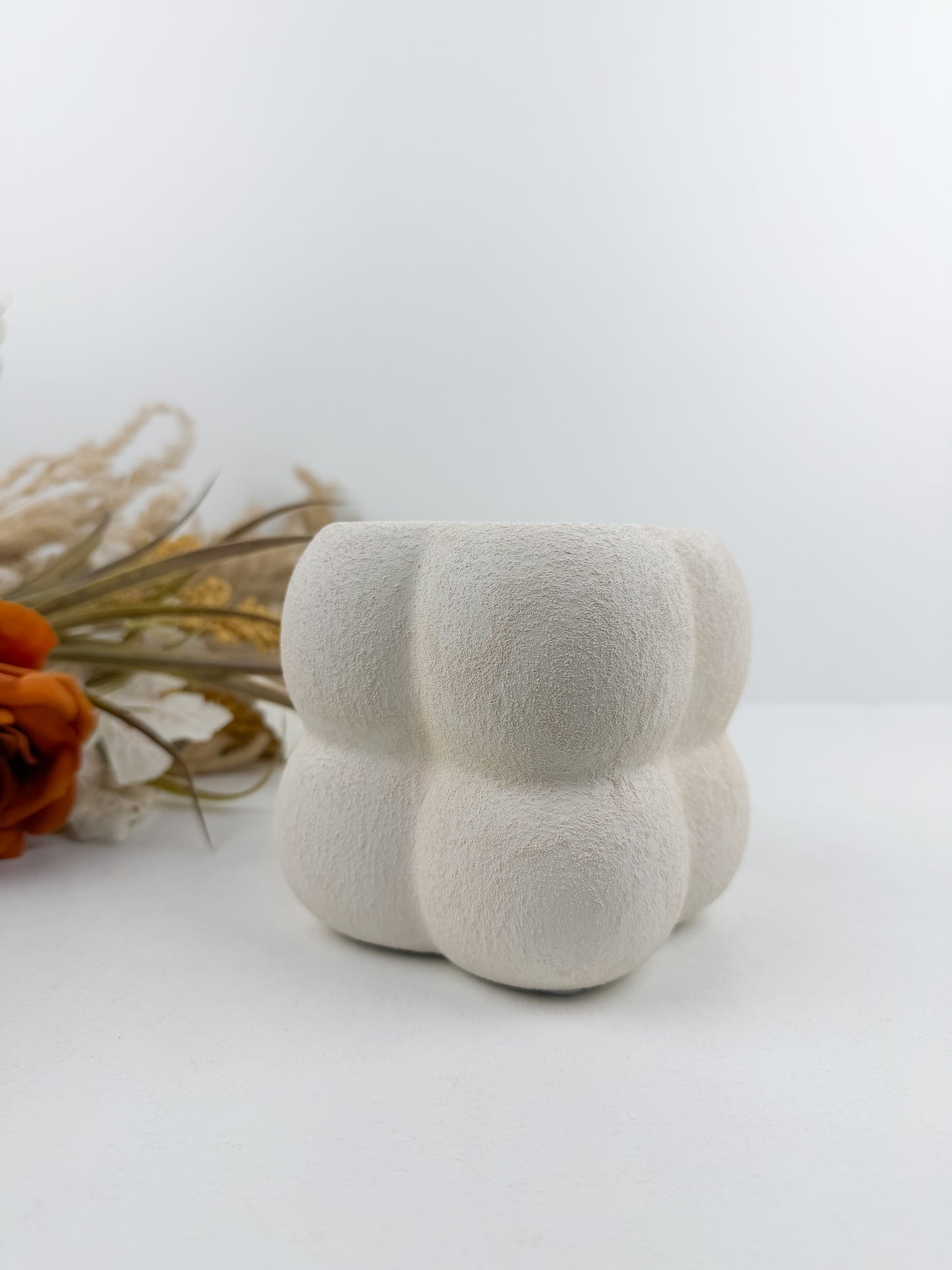 Petit vase en céramique blanc aux finitions texturées et bulles délicates.