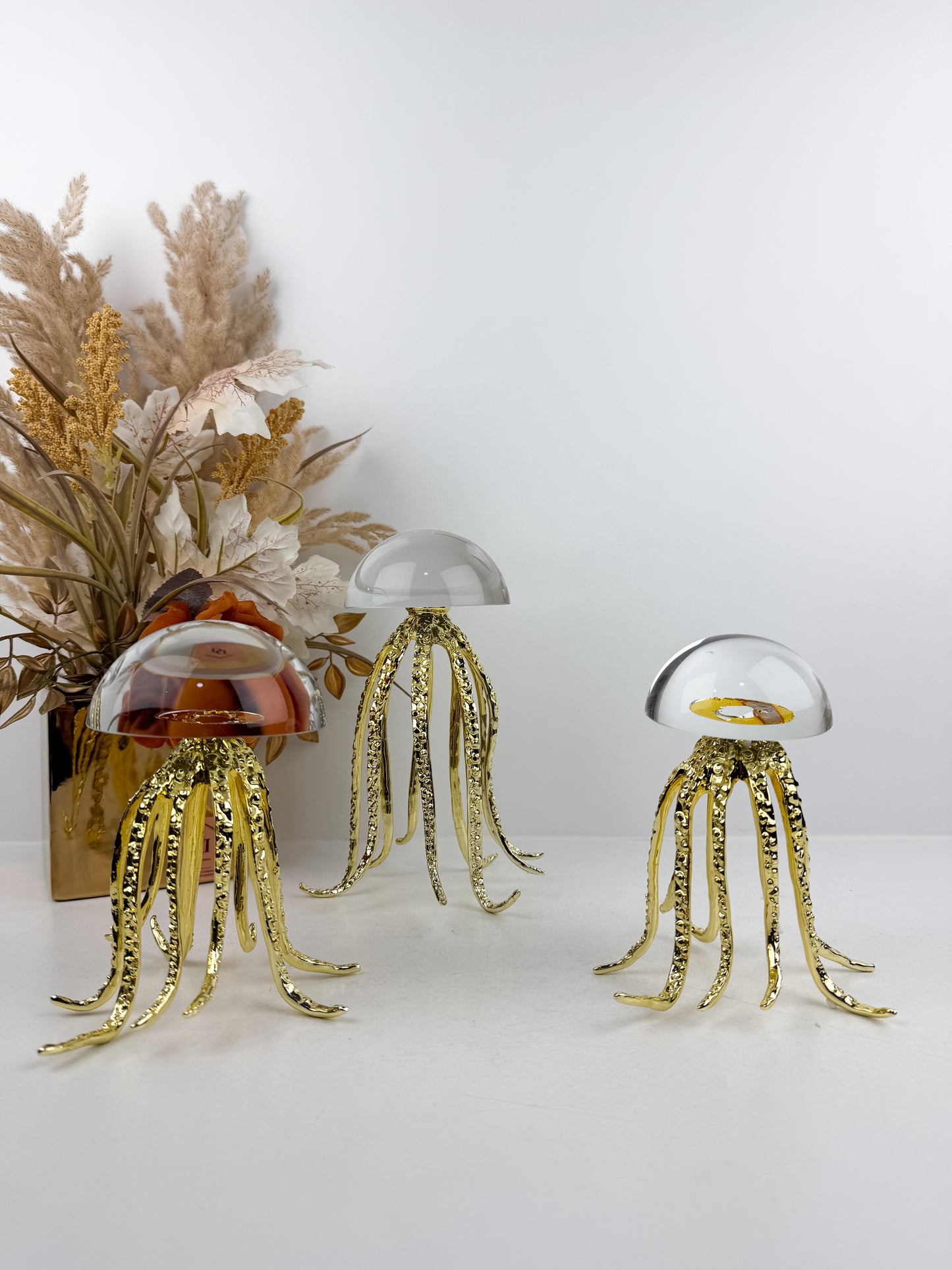 Trois sculptures de méduses dorées en métal avec un dôme en cristal