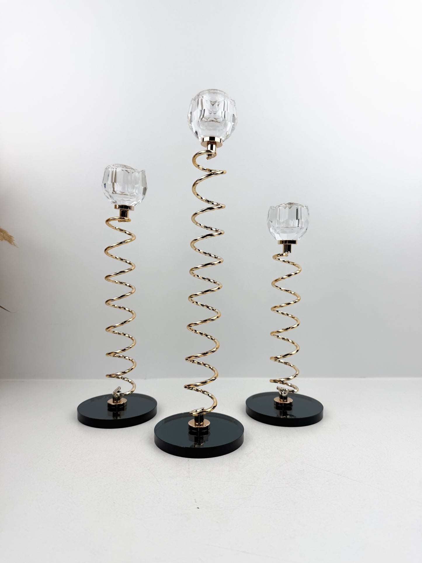 Trio de Bougeoirs en cristal doré sur un socle noir.