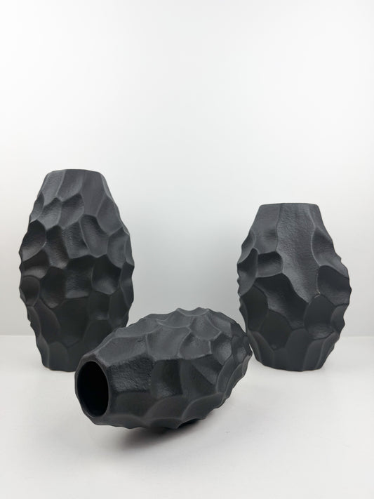 Trio de vases en noir carbone aux formes sculpturales épurées.