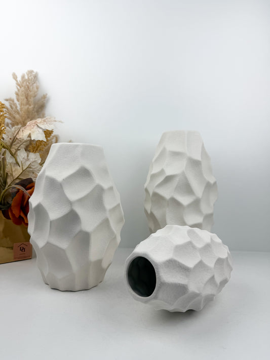Trio de vases blanches aux formes sculpturales épurées.