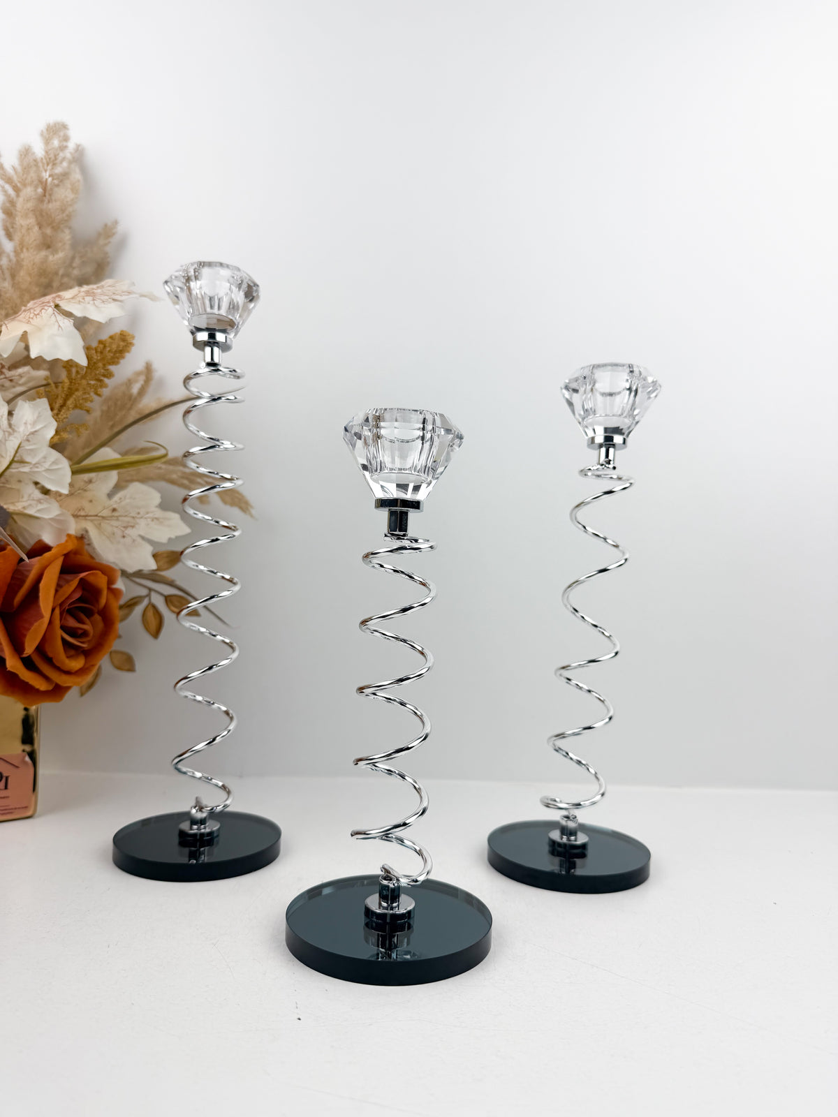 Trio de Bougeoirs en cristal argentée sur un socle noir.