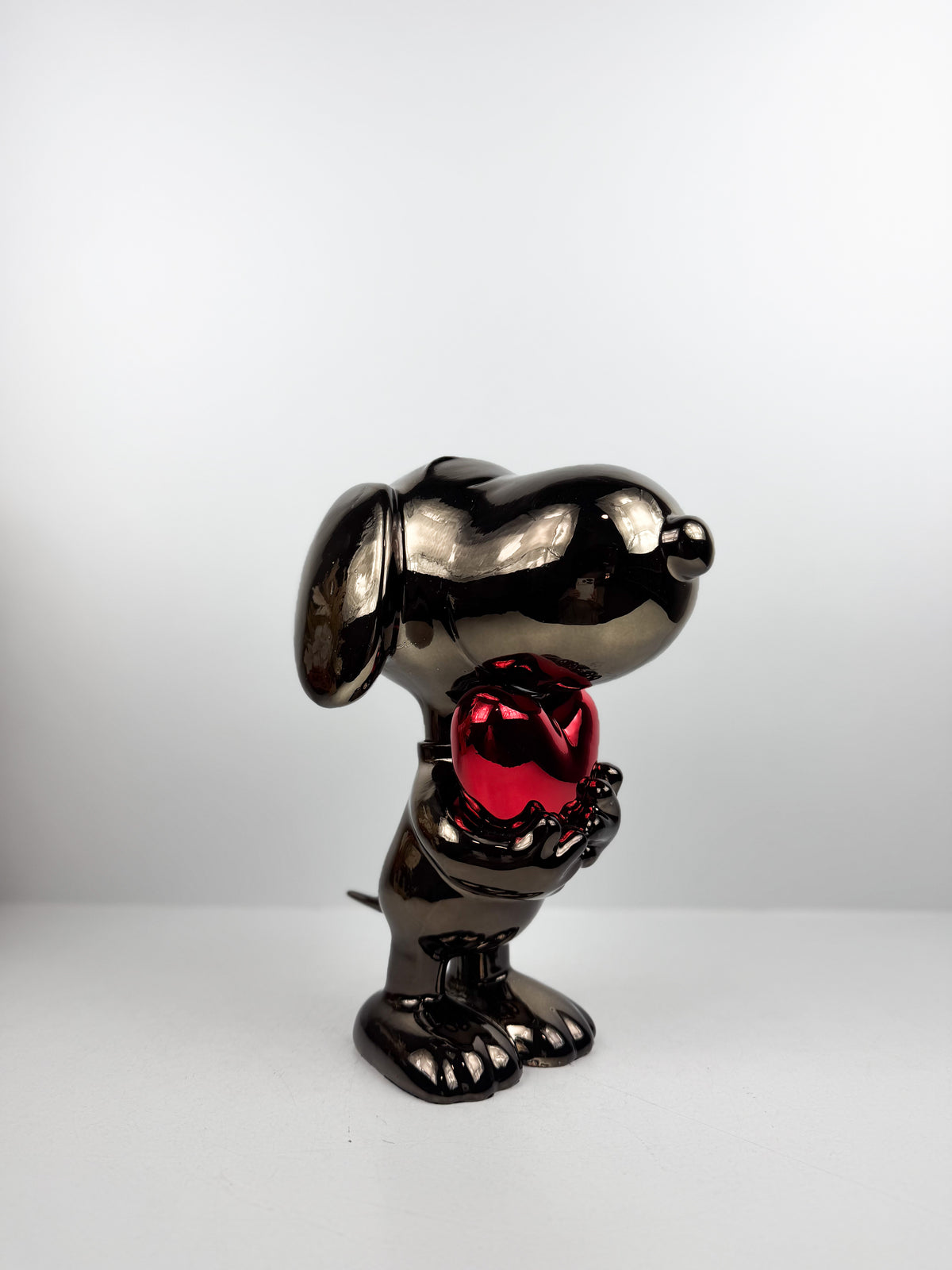 Figurine décorative représentant le célèbre personnage de Snoopy tenant un cœur.