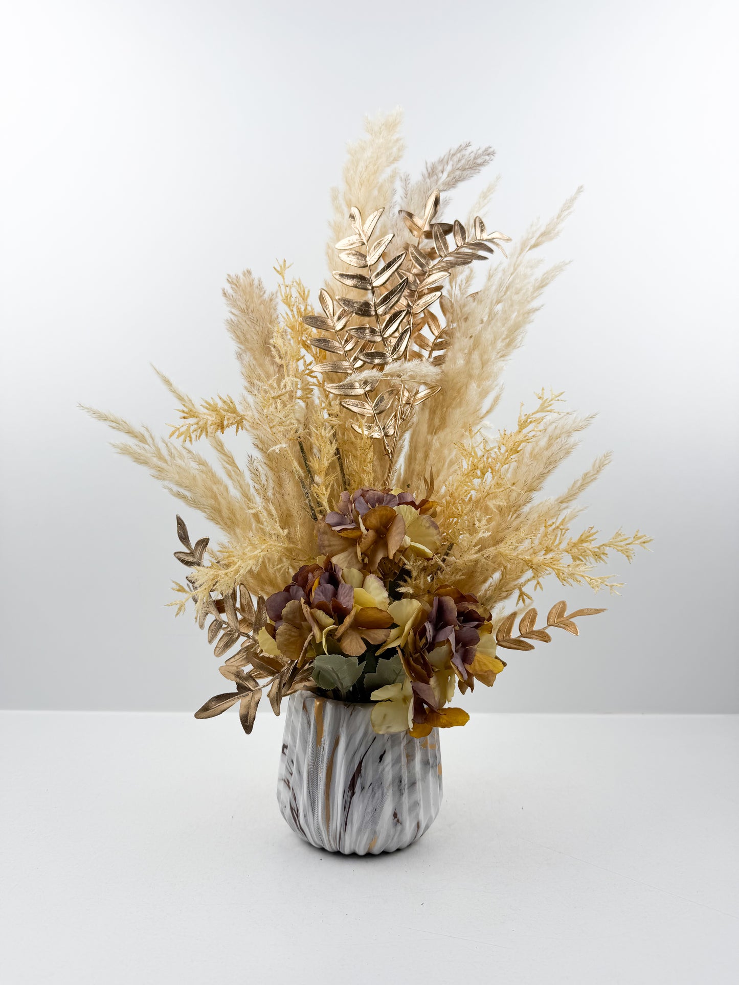 Fleurs séchés marron d'une élégance intemporelle dans un vase en forme de marbre raffiné.