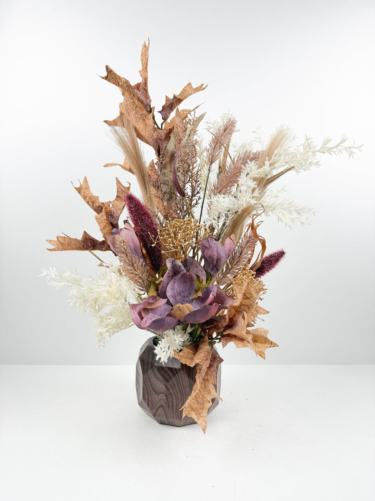 Fleurs séchées délicates dans un élégant vase géométrique en céramique.