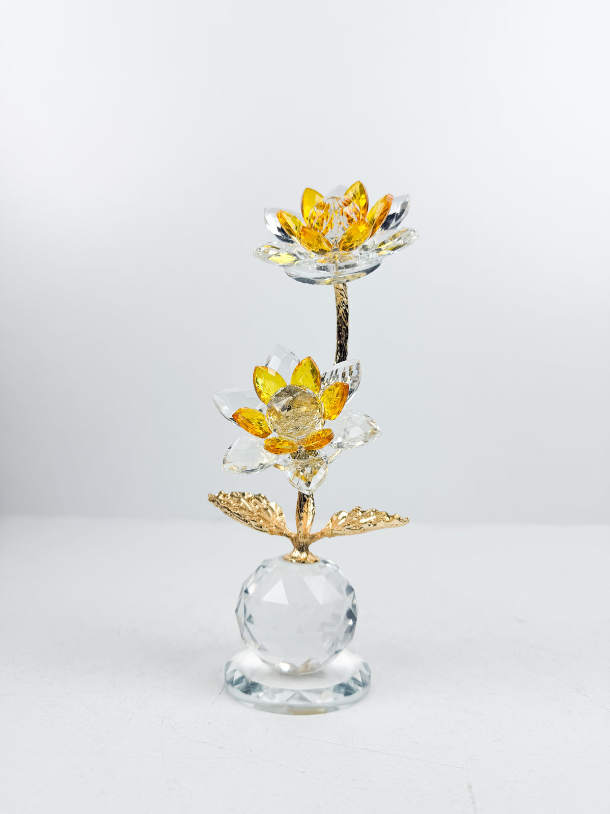 Fleur décorative dorée en cristal sur socle sphérique élégant.