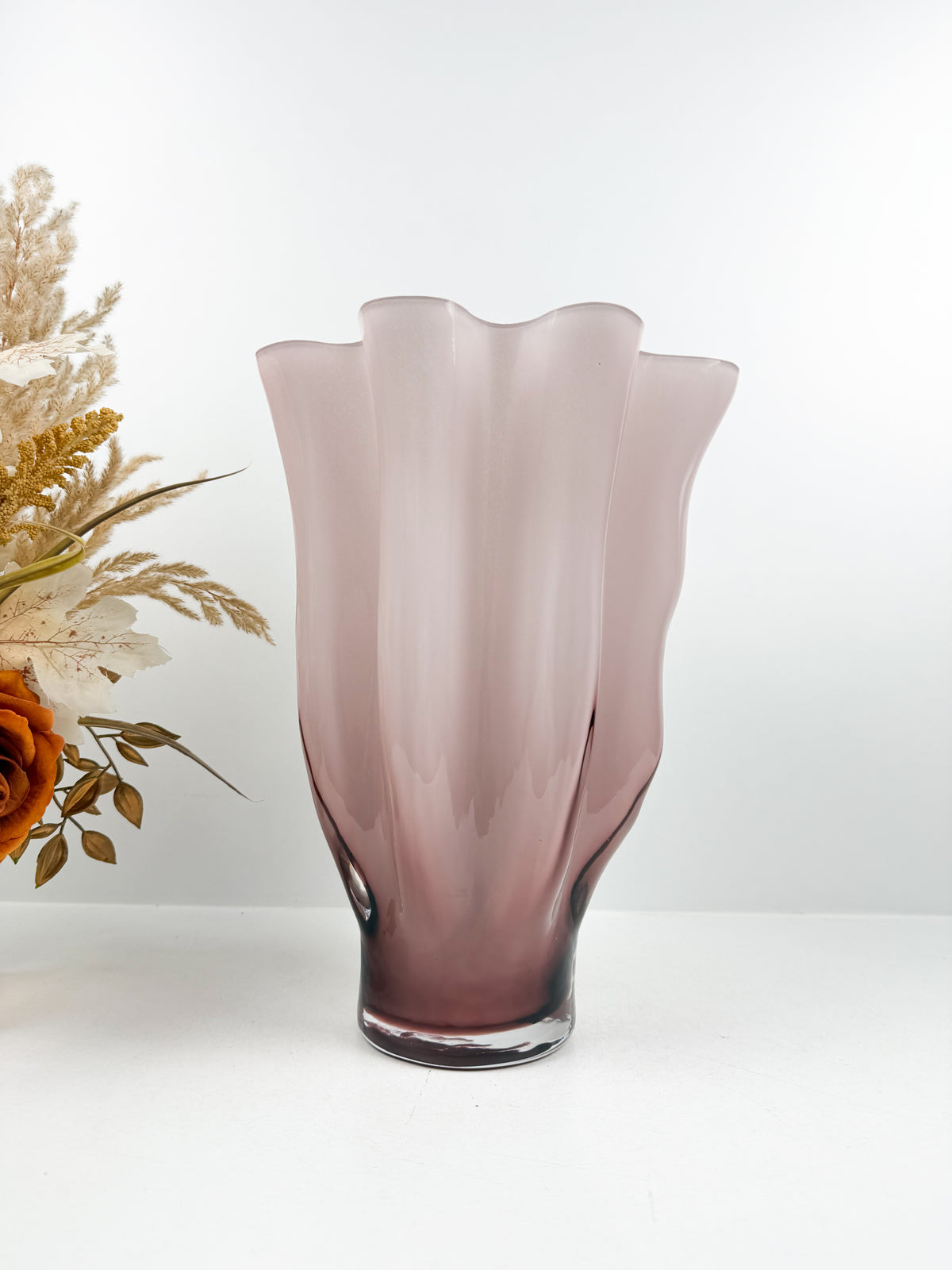 Vase décoratif sculpté rose aux bords ondulés et motifs plissés.
