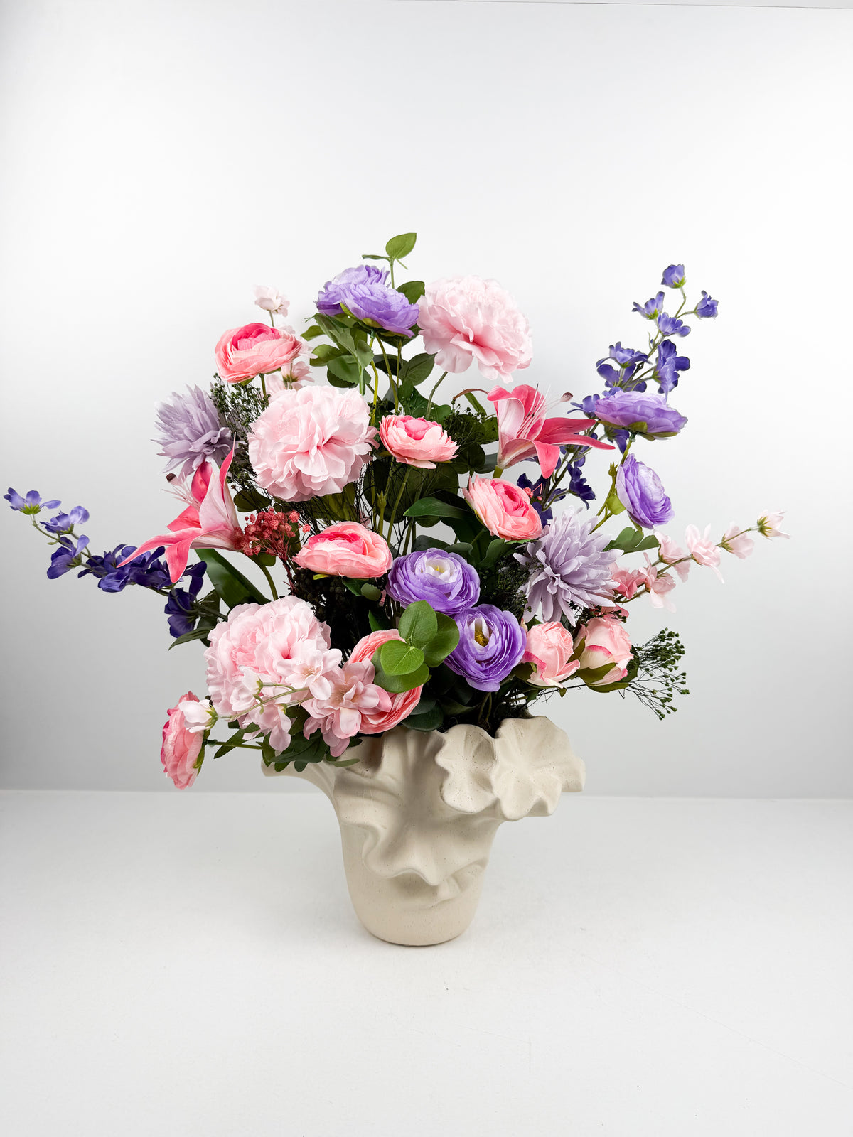 Fleurs artificielles présenté dans un original vase design sculpté en céramique à relief.
