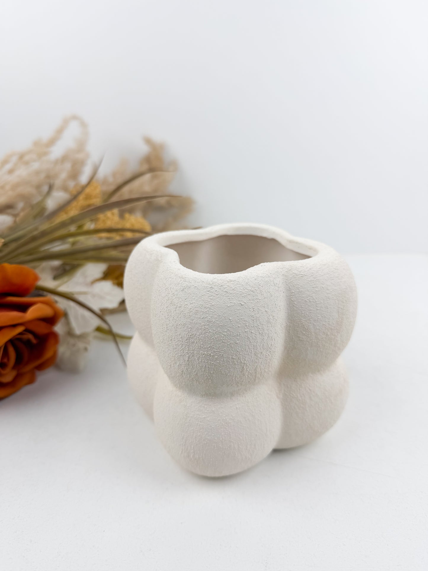 Petit vase en céramique blanc aux finitions texturées et bulles délicates.