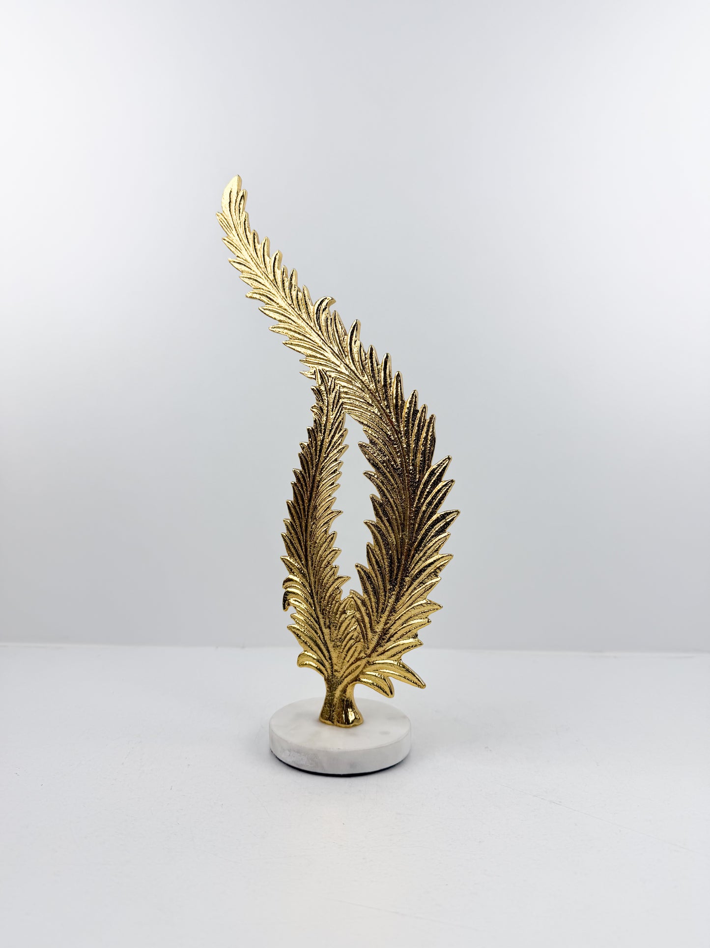 Sculpture décorative élégante représentant une feuille de fougère stylisée en métal doré.