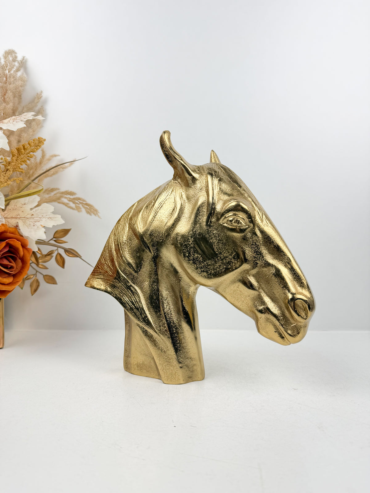 Sculpture décorative en métal doré brillant représentant une tête de cheval.