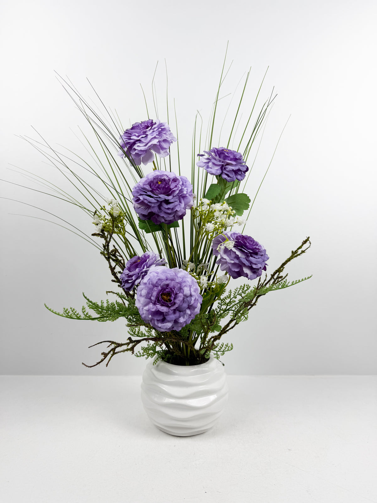 Fleurs séchées violettes délicate dans un vase en céramique aux lignes épurées.