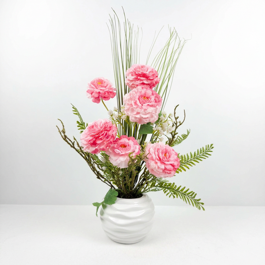 Fleurs roses raffinées présenté dans un magnifique vase en céramique blanche texturée.