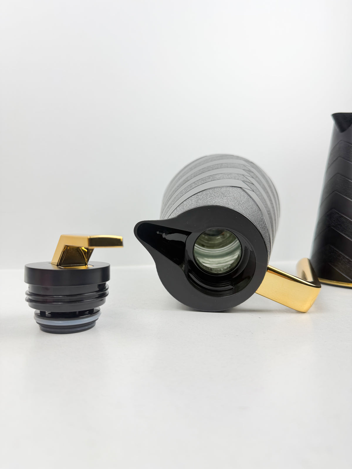 Duo de thermos isothermes noirs mats avec motifs chevrons en relief, anses et détails dorés.