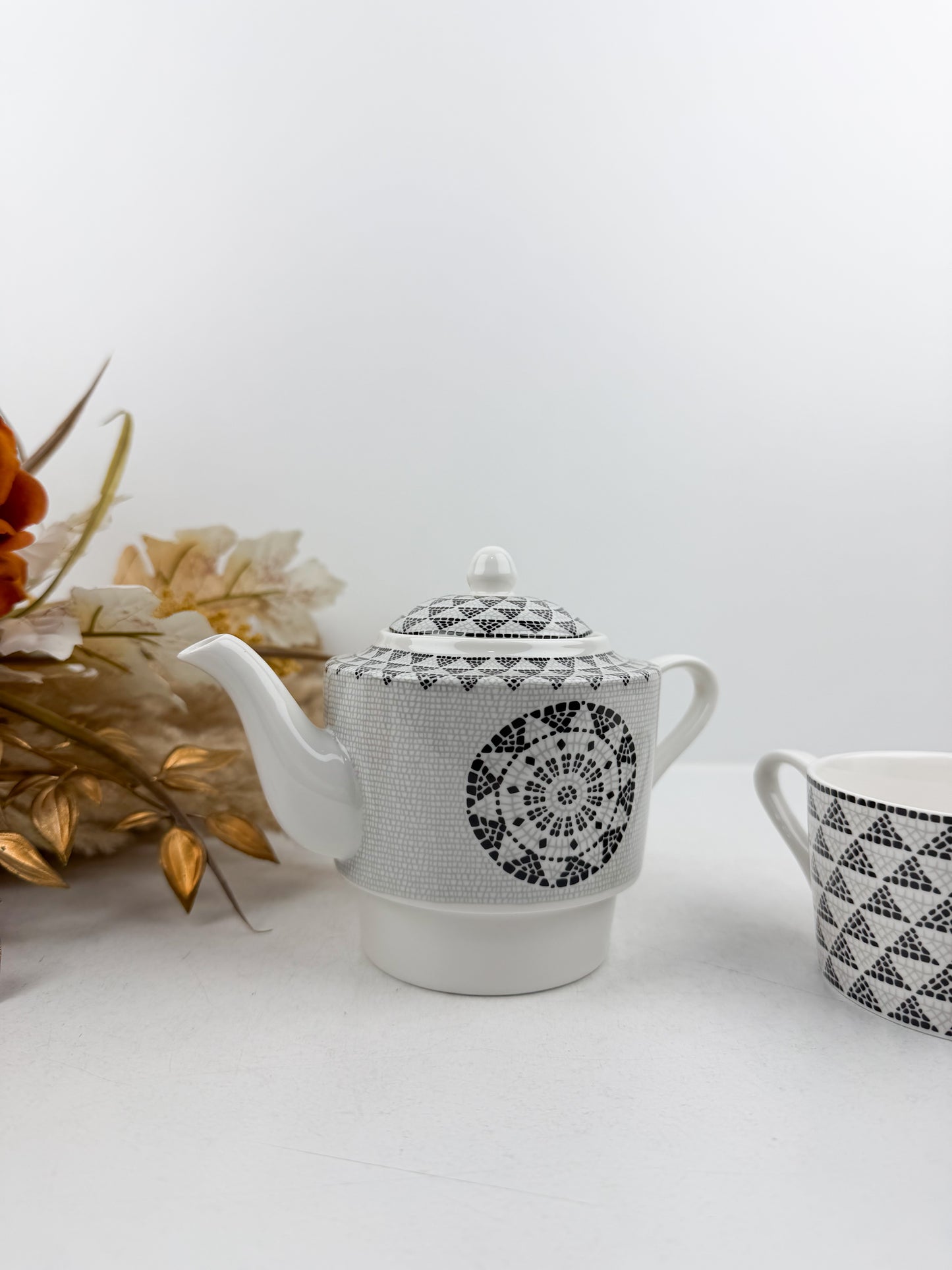 Théière élégante accompagnée d'une tasse à café au lait aux motifs treillis noir et blanc