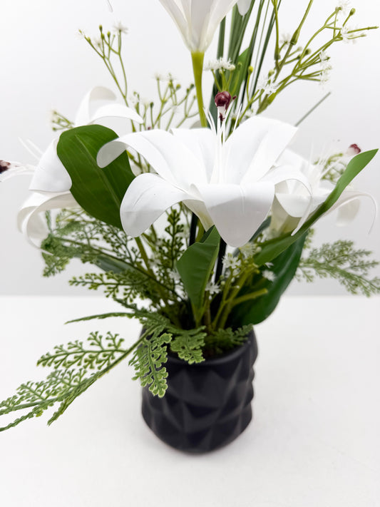 Fleurs artificielles blanches délicates dans un élégant pot noir en céramique de luxe.