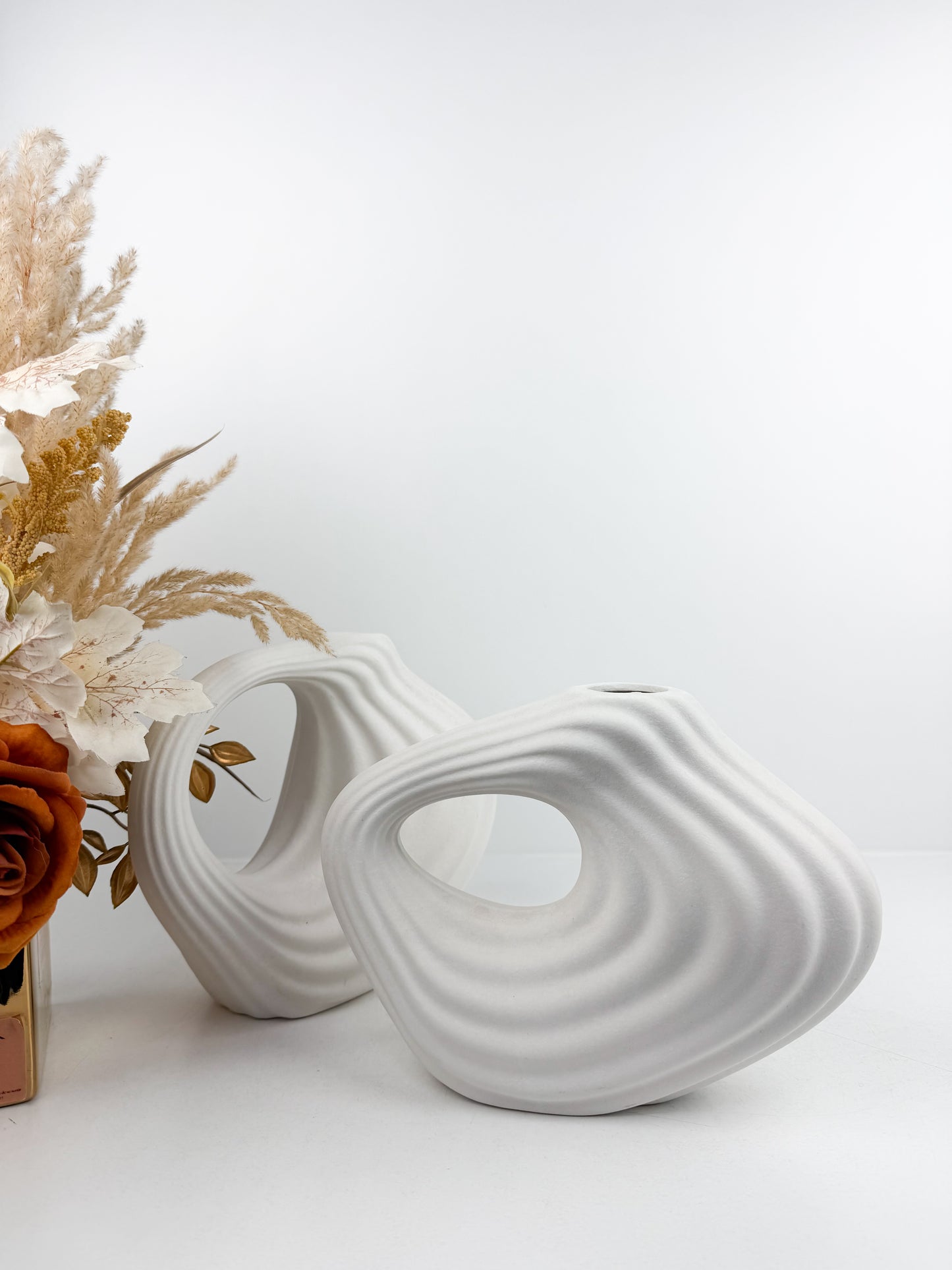 Duo de vases en céramique blanc mat aux formes géométriques épurées.