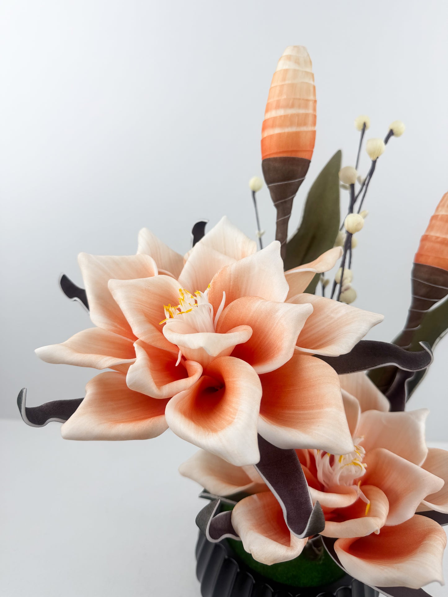 Fleurs oranges artificielles de qualité dans un pot noir haut de gamme