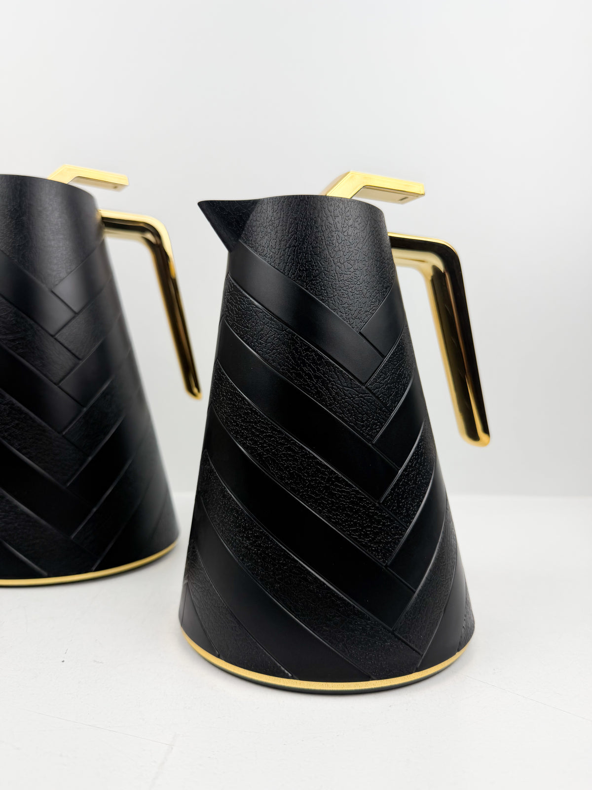 Duo de thermos isothermes noirs mats avec motifs chevrons en relief, anses et détails dorés.