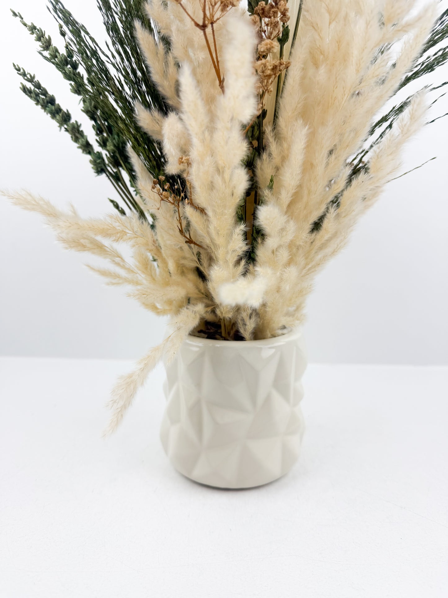 Fleurs séchées aux teintes naturelles de beige et vert, accompagnée d'un vase en céramique haut de gamme