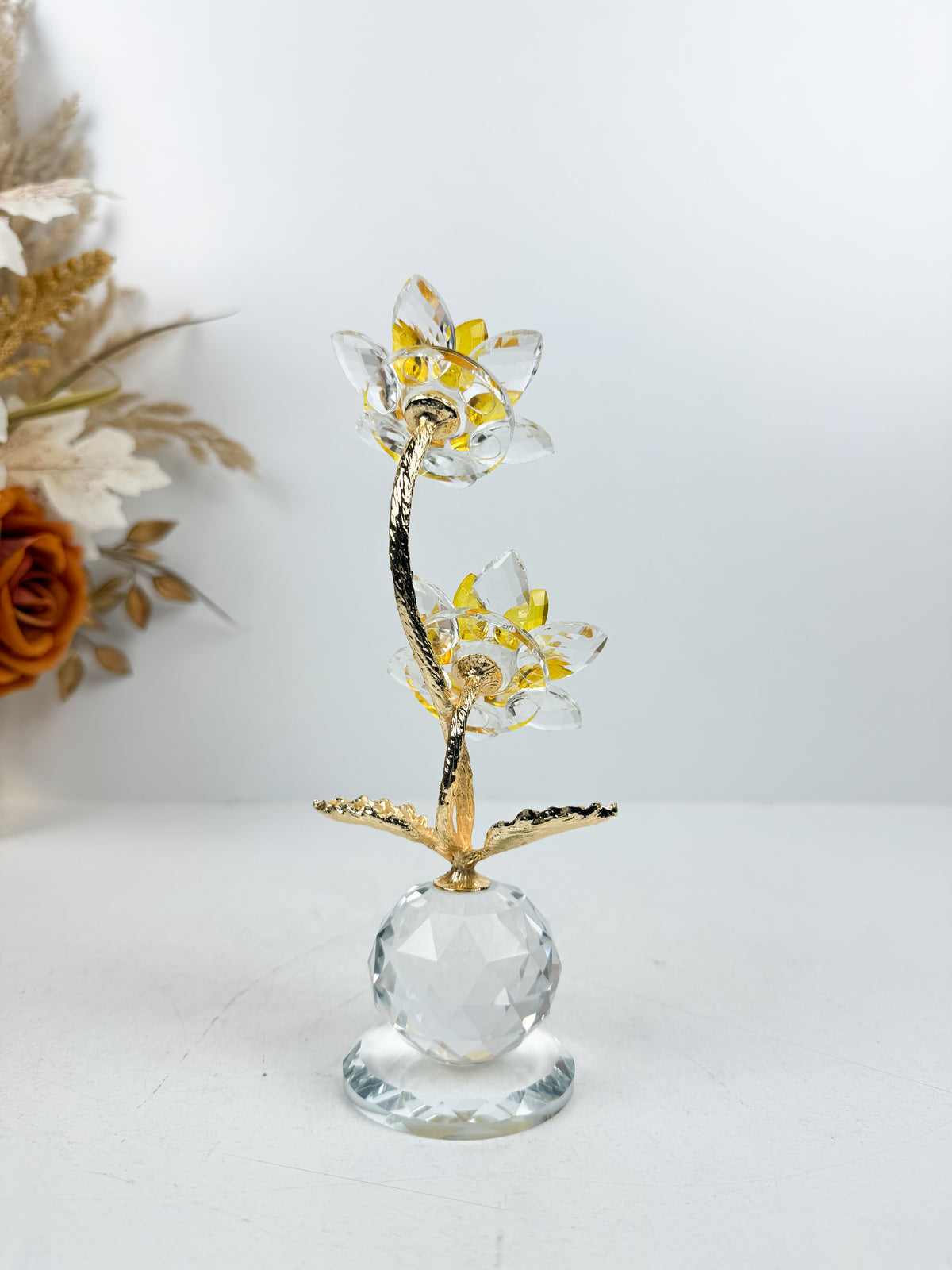 Fleur décorative dorée en cristal sur socle sphérique élégant.