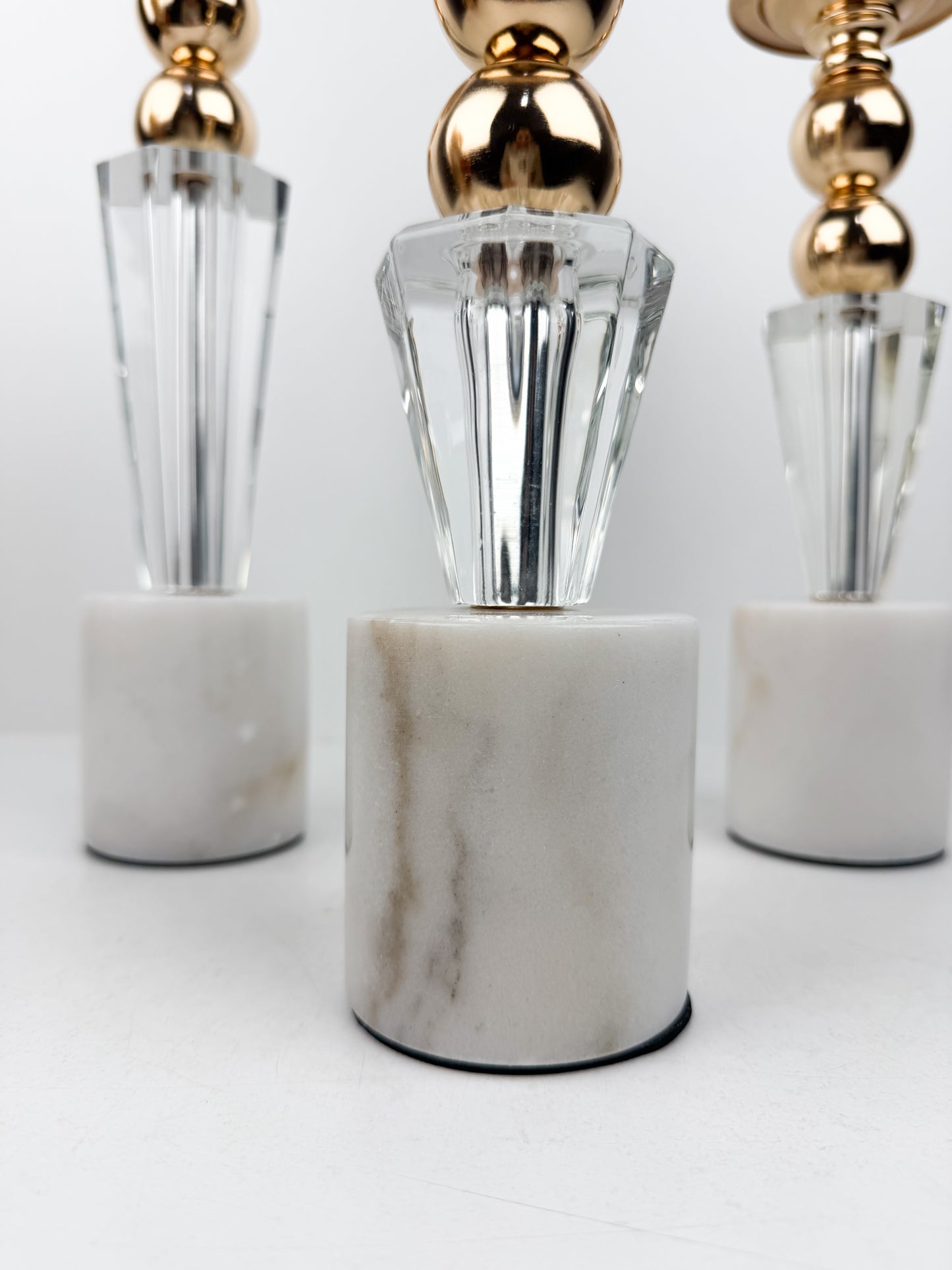 Ensemble élégant de bougeoirs en cristal et métal doré sur un socle en marbre blanc.