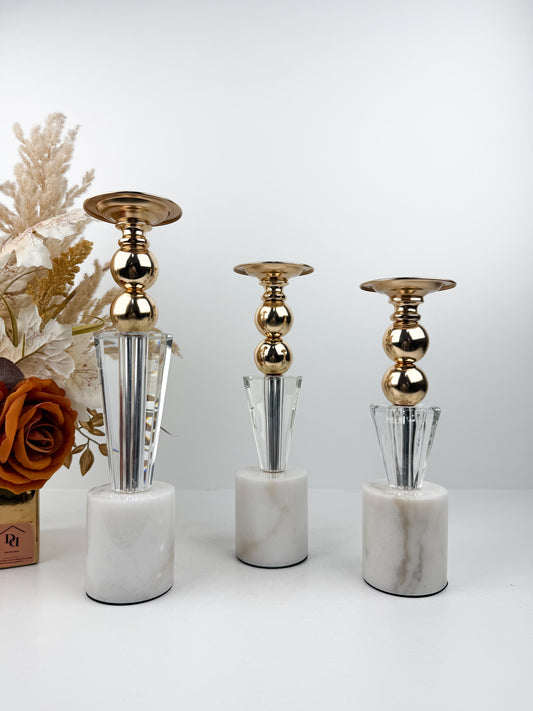Ensemble élégant de bougeoirs en cristal et métal doré sur un socle en marbre blanc.
